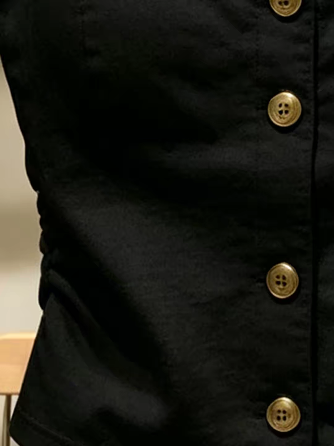 Closeup of quality black fabric and gold button front