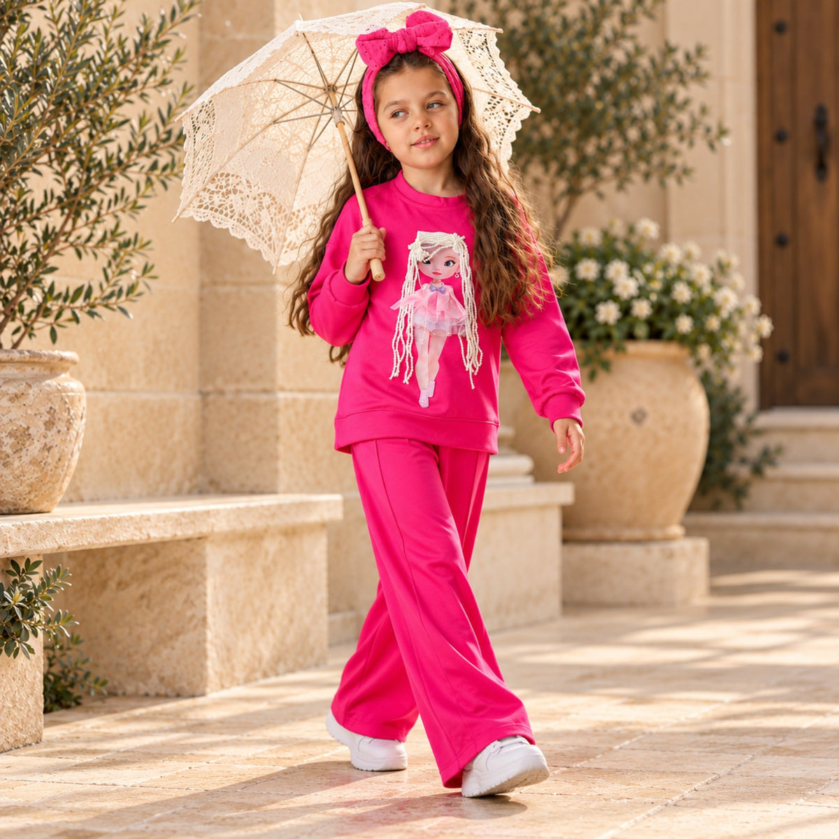 Girl in a hot pink doll print sweatshirt and wide-leg pants holding lace parasol