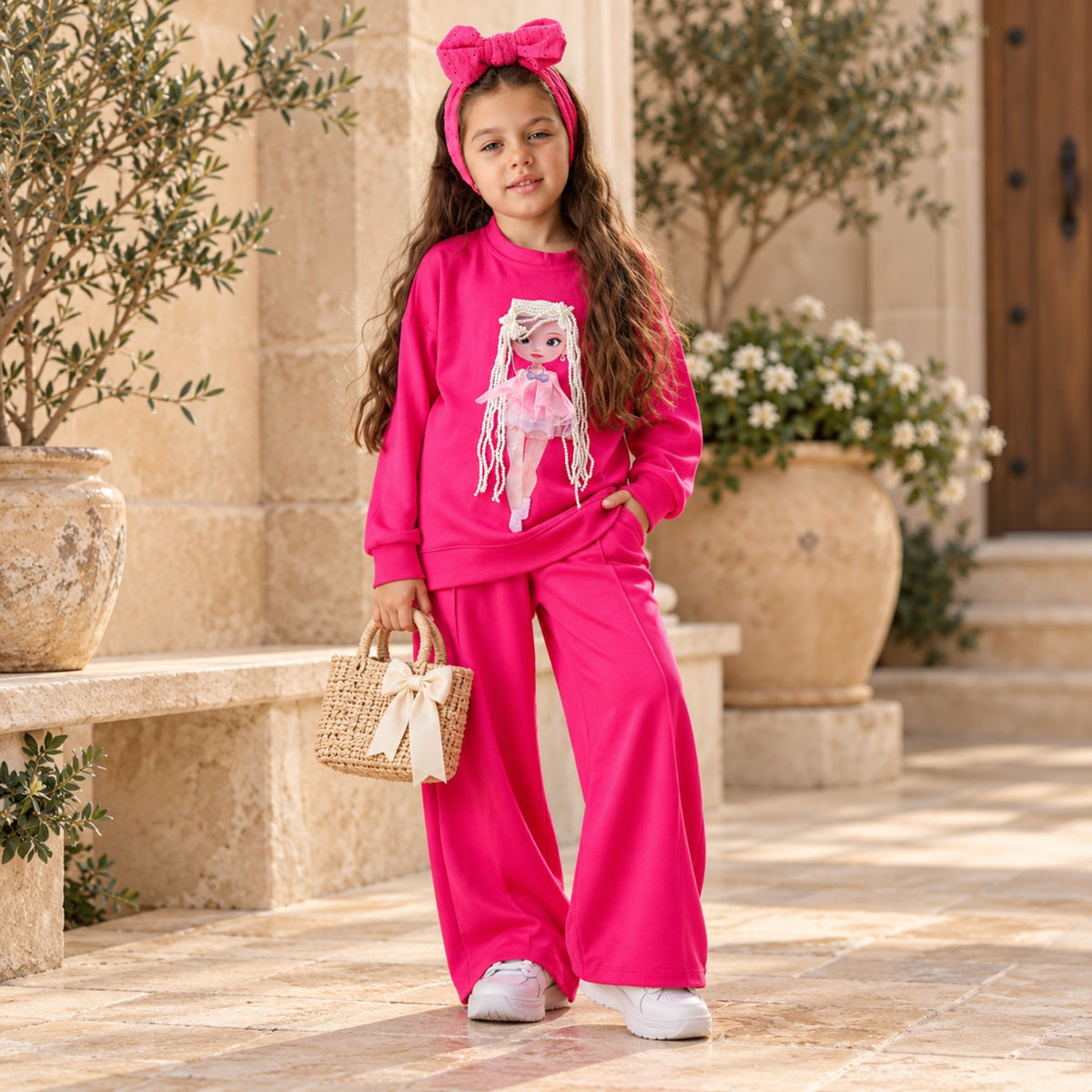 Girl wearing hot pink 3D doll sweatshirt and matching wide-leg pants outdoors, full-length view