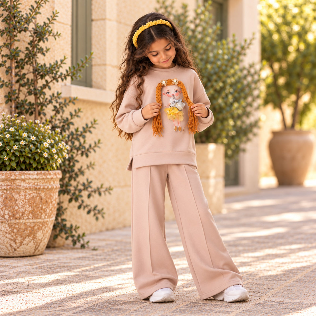 Close view of textured braided doll applique on girls beige sweatshirt