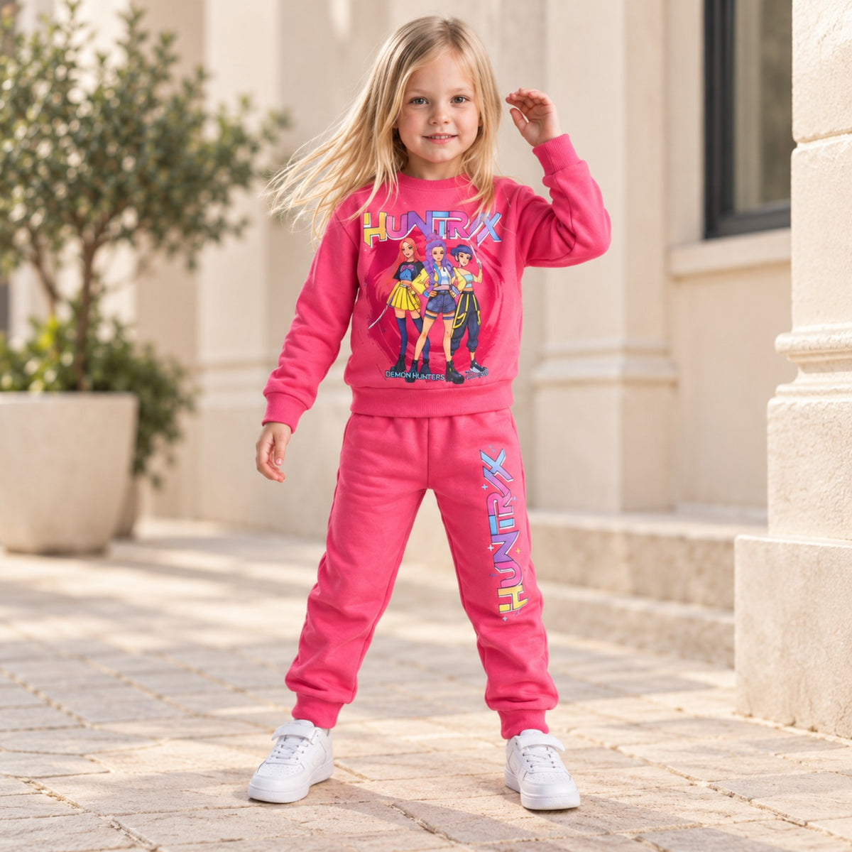 Girls hot pink HUNTR/X graphic top and matching joggers set, full-length lifestyle photo
