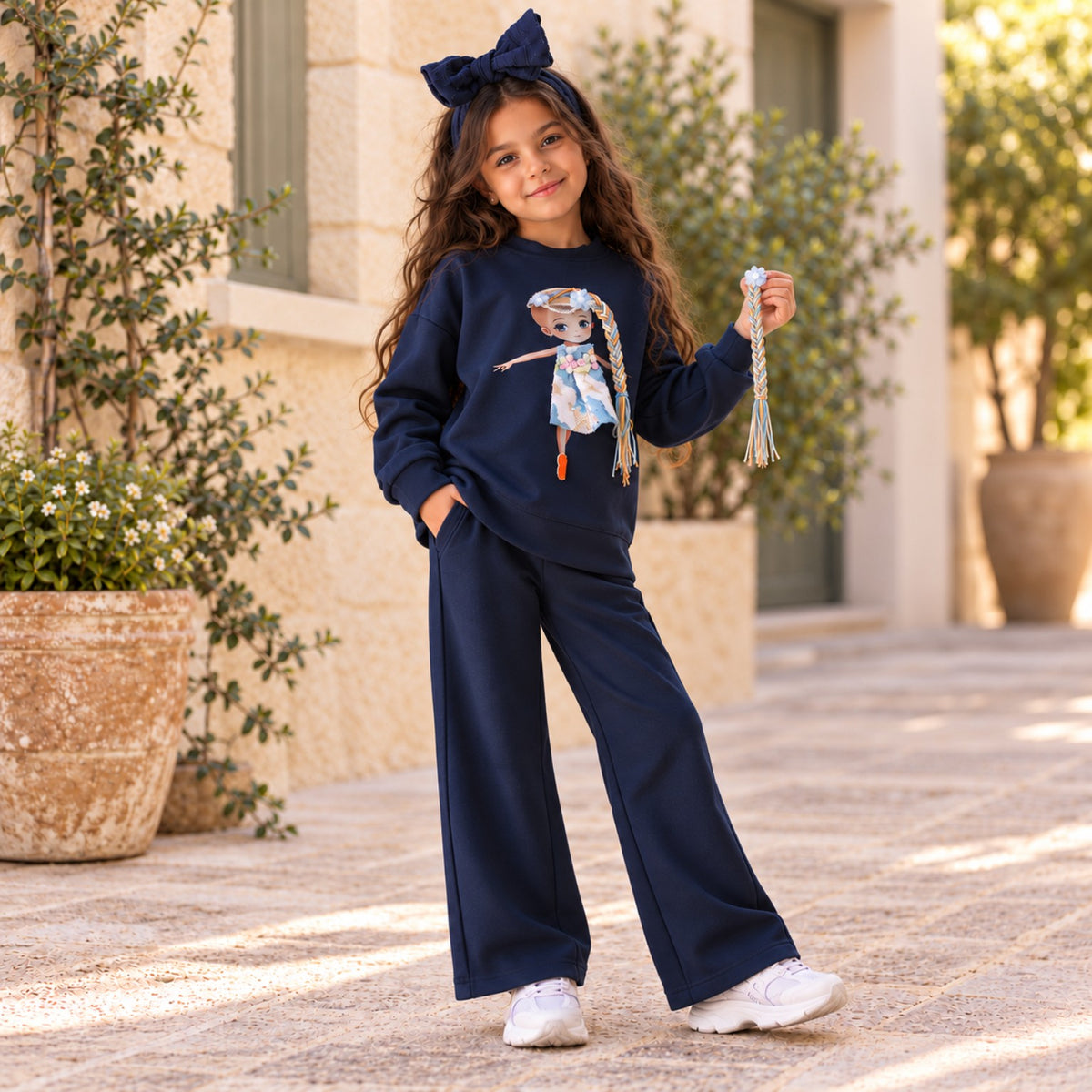 Girl displaying one of the detachable yarn braids on navy doll sweatshirt