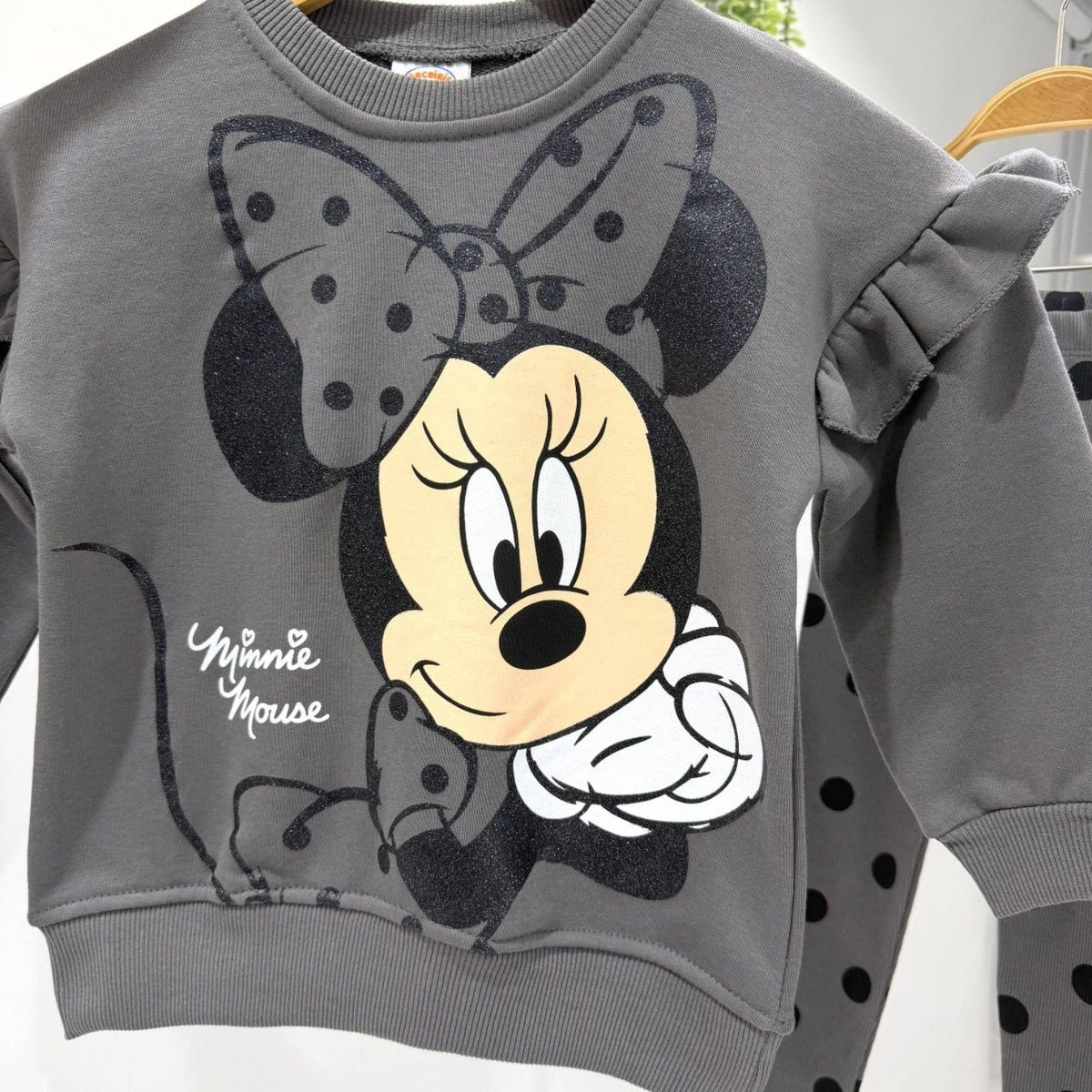 Detail of Minnie Mouse print and shoulder ruffles on grey sweatshirt